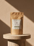 KAIA Origin premium matcha powder 80g pouch on travertine pedestal, Belgian stone-ground matcha